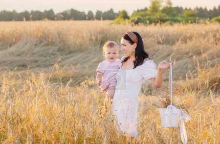 Téléchargez les photos : Femme heureuse avec petite fille sur le champ d'été au coucher du soleil - en image libre de droit