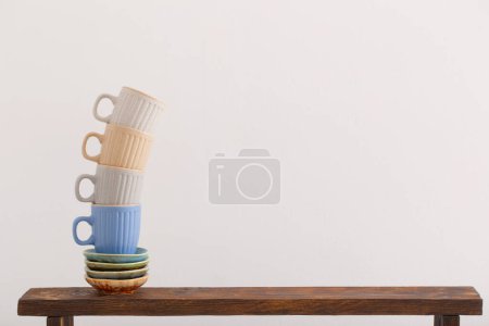 Foto de Tazas de colores en estante de madera sobre fondo blanco - Imagen libre de derechos