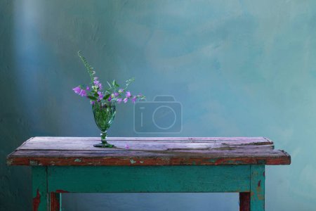Téléchargez les photos : Fleurs bluebell dans un vase en verre vert sur une vieille table en bois - en image libre de droit