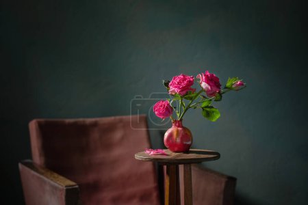 Photo for Pink roses in pink vase with old armchair on background dark   wall - Royalty Free Image