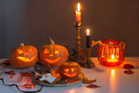 Téléchargez les photos : Citrouilles halloween avec des bougies allumées sur table blanche - en image libre de droit