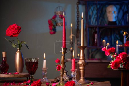 Photo for Magic potion with red roses and burning candles in dark room - Royalty Free Image