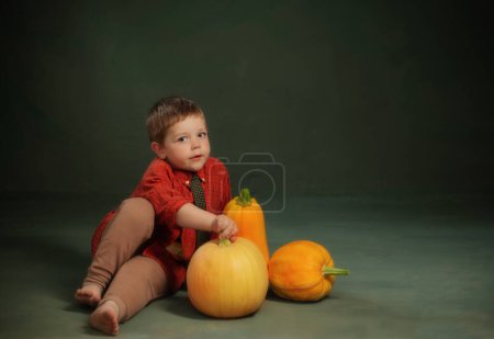Foto de Niño pequeño con calabazas sobre fondo verde oscuro - Imagen libre de derechos