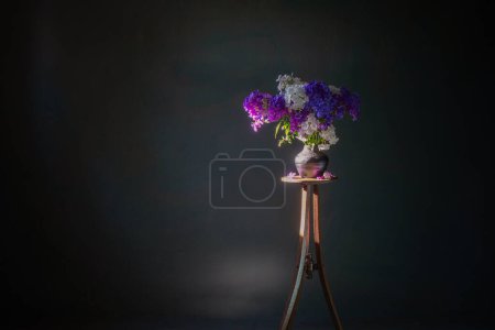 Photo for Phloxes in vase on vintage wooden shelf  on dark background - Royalty Free Image
