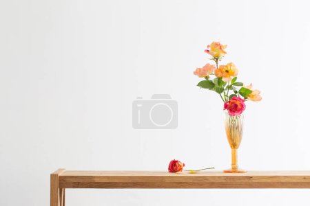 Foto de Rosas naranjas y rosas en jarrón de cristal en el interior blanco - Imagen libre de derechos