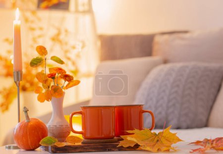 Foto de Dos tazas de naranja con bebida caliente en el interior de la luz otoñal - Imagen libre de derechos