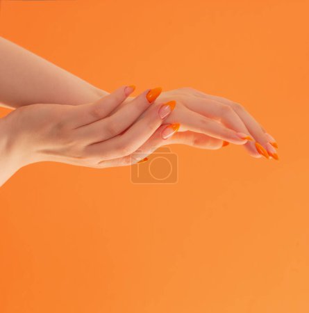 Téléchargez les photos : Main féminine avec manucure sur fond orange - en image libre de droit