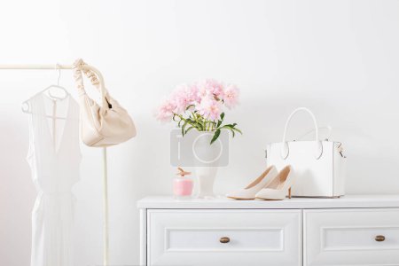 Foto de Vestidor blanco con ropa y flores en habitación blanca - Imagen libre de derechos