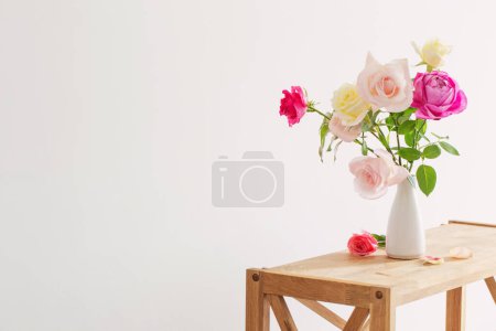 Téléchargez les photos : Roses roses et blanches dans un vase en céramique blanche sur fond blanc - en image libre de droit