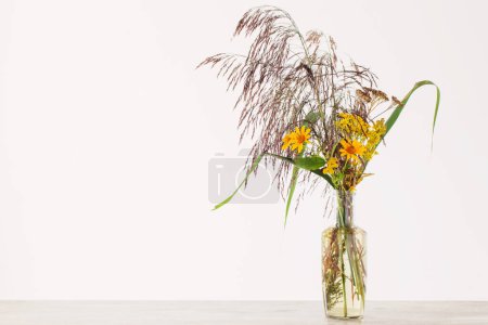 Foto de Ramo de cañas y flores otoñales amarillas en botella sobre fondo blanco - Imagen libre de derechos