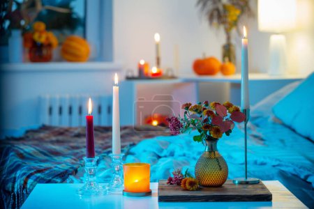 Photo for Autumnal chrysanthemum in vase with burning candles in bedroom - Royalty Free Image