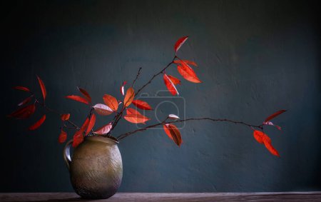 Foto de Hojas rojas de otoño en jarra de cerámica sobre una vieja mesa de madera - Imagen libre de derechos