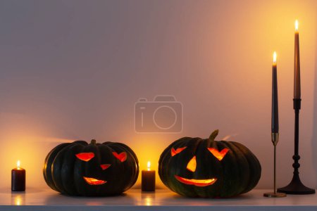 Photo for Black halloween pumpkin with burning candles in white interior - Royalty Free Image