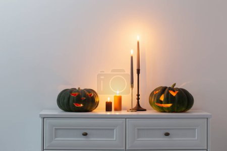 Foto de Calabaza de halloween negro con velas encendidas en el interior blanco - Imagen libre de derechos