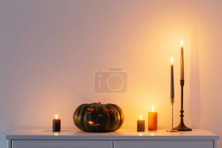 Photo for Black halloween pumpkin with burning candles in white interior - Royalty Free Image