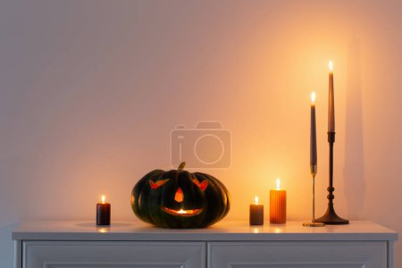 Téléchargez les photos : Citrouille noire halloween avec des bougies allumées à l'intérieur blanc - en image libre de droit