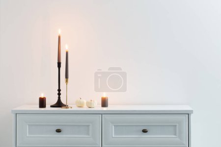 Foto de Velas ardientes en estante de madera blanca en el interior blanco - Imagen libre de derechos