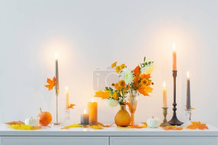 Photo for Beautiful autumn home decor with burning candles in white interior - Royalty Free Image