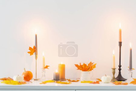 Foto de Hermosa decoración casera de otoño con velas encendidas en el interior blanco - Imagen libre de derechos