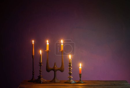Photo for Burning candles in vintage candlesticks on dark background - Royalty Free Image