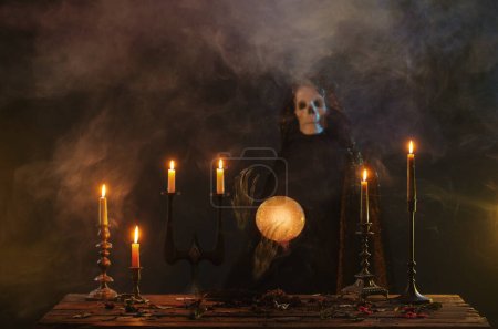 Foto de La muerte predice el futuro con bola de cristal en habitación oscura - Imagen libre de derechos