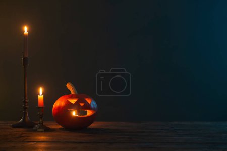 Téléchargez les photos : Citrouilles d'Halloween avec des bougies allumées sur fond sombre - en image libre de droit