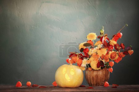 Photo for Funny halloween pumpkin with autumnal bouquet on dark background - Royalty Free Image