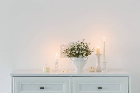 Téléchargez les photos : Fleurs blanches dans un vase en céramique blanche avec des bougies allumées à l'intérieur blanc - en image libre de droit