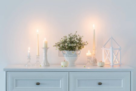 Téléchargez les photos : Fleurs blanches dans un vase en céramique blanche avec des bougies allumées à l'intérieur blanc - en image libre de droit