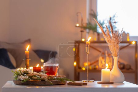 thé chaud en verre thermique avec décor de Noël et bougies allumées à la maison