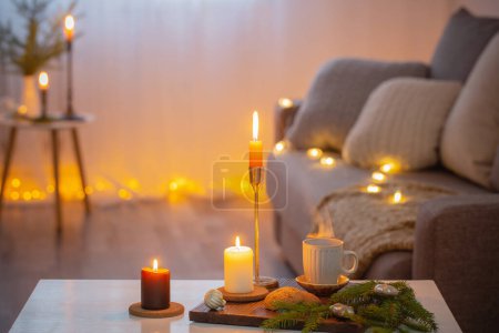 Foto de Taza de café con velas encendidas y decoraciones navideñas en casa - Imagen libre de derechos