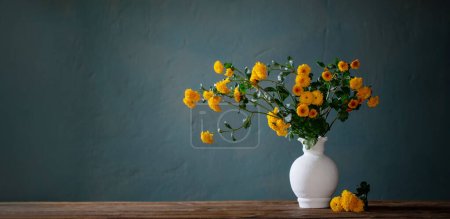 Téléchargez les photos : Chrysanthèmes jaunes dans un vase blanc sur fond sombre mur - en image libre de droit