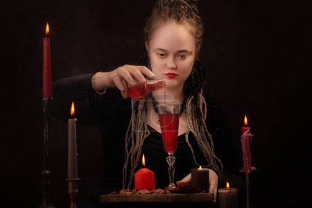 Photo for Young witch with love potoin  on dark background - Royalty Free Image