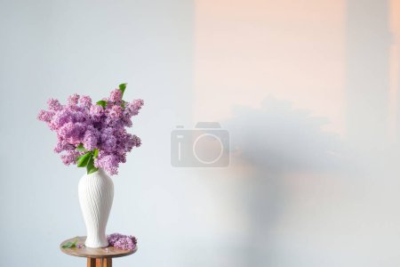 Téléchargez les photos : Fleurs lilas en vase blanc sur fond blanc mur - en image libre de droit