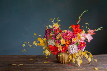 Autumn bouquet with red and yellow flowers in ceramic vase on dark background