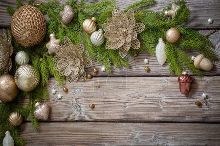 Téléchargez les photos : Jouets de Noël dorés avec branches de sapin sur fond de bois foncé - en image libre de droit