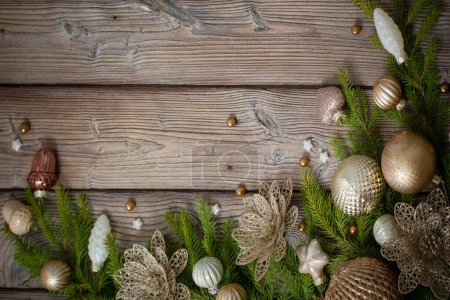 Téléchargez les photos : Jouets de Noël dorés avec branches de sapin sur fond de bois foncé - en image libre de droit