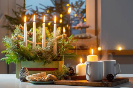 Foto de Tazas blancas con bebidas calientes y decoraciones navideñas en casa - Imagen libre de derechos