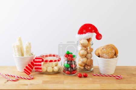Téléchargez les photos : Bonbons de Noël et biscuits dans des pots sur une étagère en bois sur fond blanc - en image libre de droit