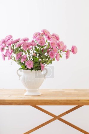 Foto de Crisantemos rosados en jarrón blanco sobre interior blanco - Imagen libre de derechos