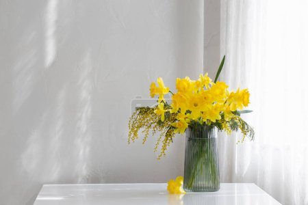 Foto de Flores amarillas de primavera en jarrón de vidrio sobre fondo blanco - Imagen libre de derechos