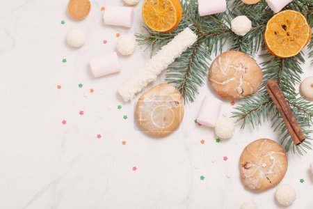 Foto de Caramelos y galletas con ramas de árbol de Navidad sobre fondo de mármol blanco - Imagen libre de derechos