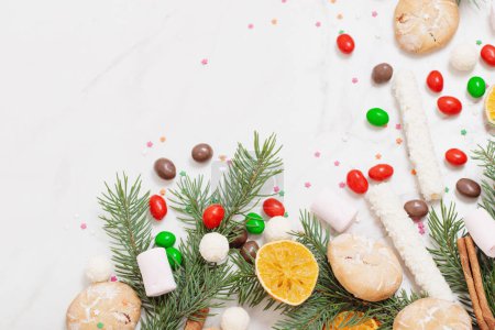 Téléchargez les photos : Bonbons et biscuits avec branches d'arbre de Noël sur fond de marbre blanc - en image libre de droit