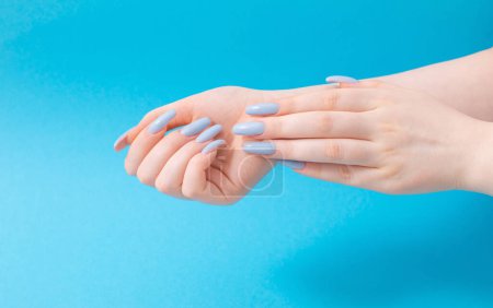 Photo for Female hands with beautiful blue manicure  on blue background - Royalty Free Image