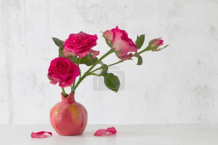 Téléchargez les photos : Roses roses en vase rose sur fond vieux mur blanc - en image libre de droit