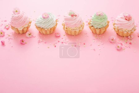 Téléchargez les photos : Cupcakes roses et verts avec des fleurs printanières sur fond rose - en image libre de droit