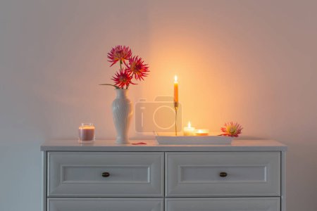 Téléchargez les photos : Magnifique dahlia rose dans un vase blanc et des bougies allumées sur fond blanc - en image libre de droit