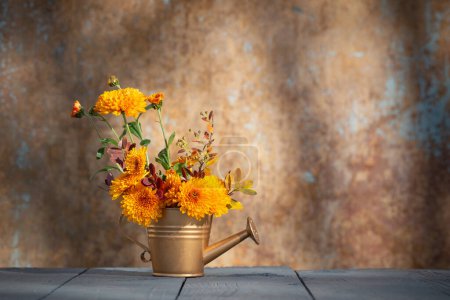 Téléchargez les photos : Fleurs de chrysanthème en arrosoir doré sur fond vieux mur à la lumière du soleil - en image libre de droit