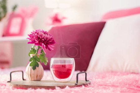 Téléchargez les photos : Thé rouge en verre thermique avec des fleurs dans la chambre moderne dans la couleur tendance de l'année 2023 - en image libre de droit