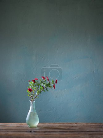 Téléchargez les photos : Chrysanthèmes rouges dans un vase en verre sur fond sombre - en image libre de droit